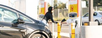 Person in front of electric vehicle and chargers completing charging session