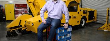 Mike Terzo, CEO of Terzo Power Systems, posing with lithium-ion battery packs in front of a prototype CNG hybrid-electric nut harvester