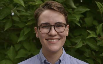 headshot of Dem Ruthrauff posed with green leaves in the background