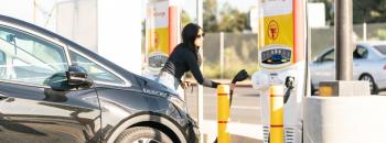 Person in front of electric vehicle and chargers completing charging session